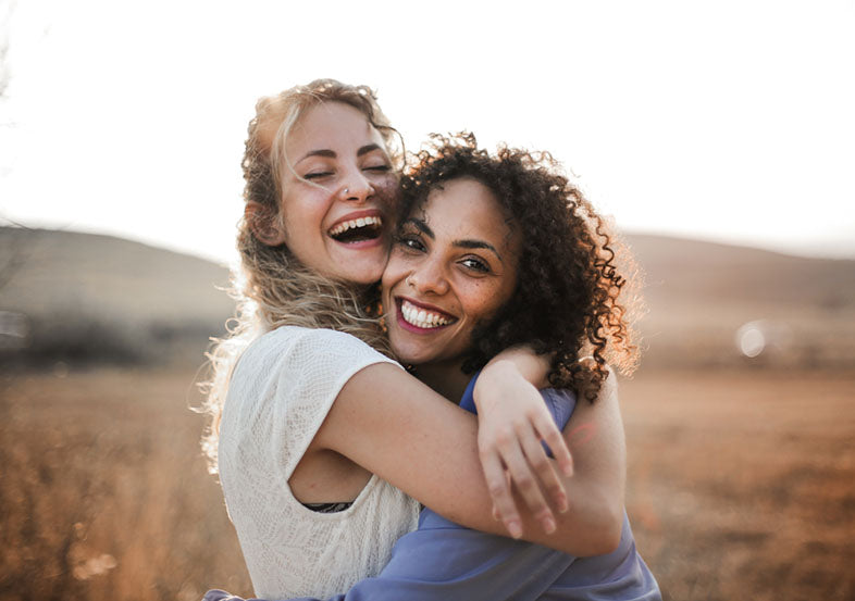 smiling friends hugging outdoors